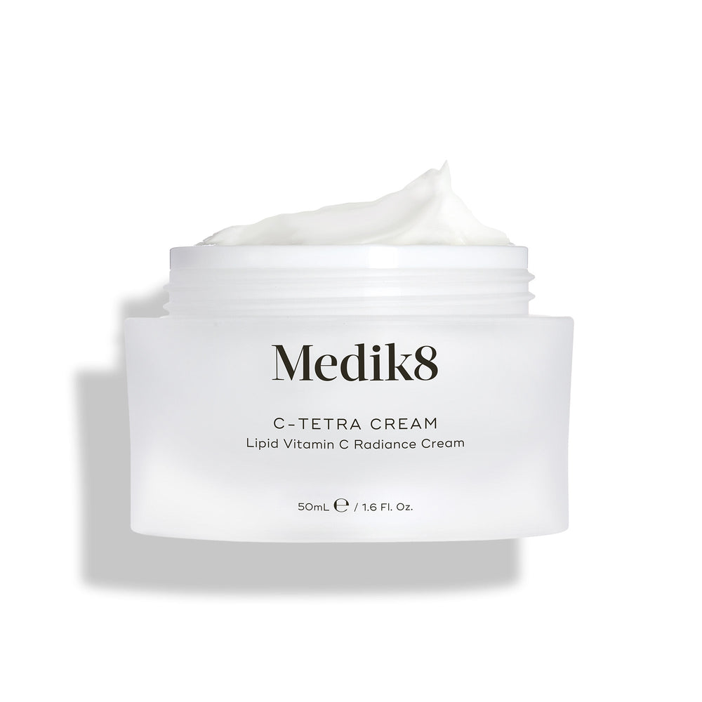 Medik8 C-Tetra Cream jar displayed open against a clean white background with soft shadows. The white, frosted-glass jar features the Medik8 logo and is labeled  C-TETRA CREAM Lipid Vitamin C Radiance Cream  in a 50mL size. A thick swirl of white cream is visible on top of the jar, highlighting its moisturising texture.
