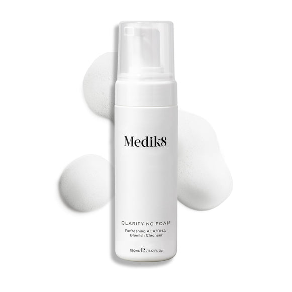 Medik8 Clarifying Foam pump bottle displayed on a clean white background with three dollops of white airy foam. Text identifies it as a Refreshing AHA/BHA Blemish Cleanser in a 150mL size.-25