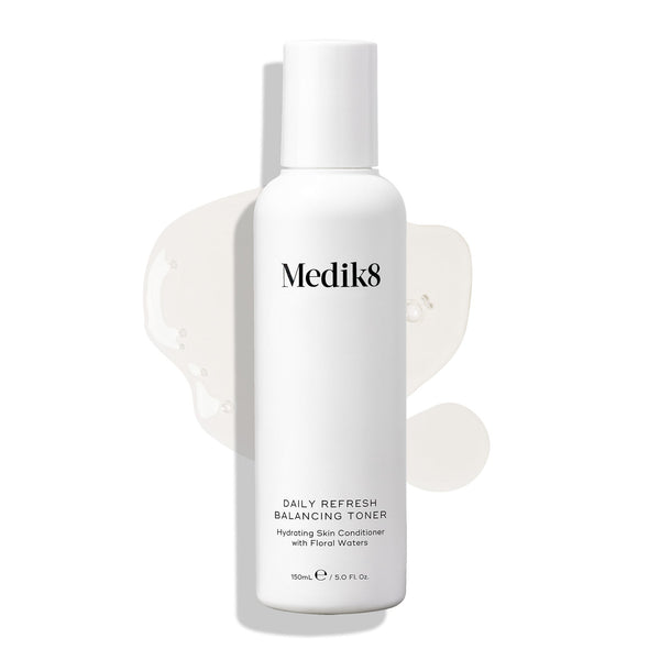 Medik8 Daily Refresh Balancing Toner bottle stands on a white background with a clear liquid spill. Text identifies it as a  Hydrating Skin Conditioner with Floral Waters  in a 150mL size.