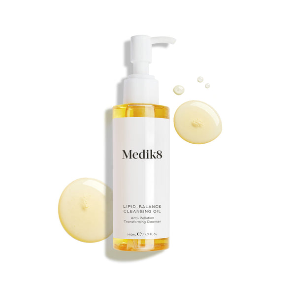 Medik8 Lipid-Balance Cleansing Oil bottle stands against a white background. Golden oil droplets surround the bottle, highlighting its rich, fluid texture.-20