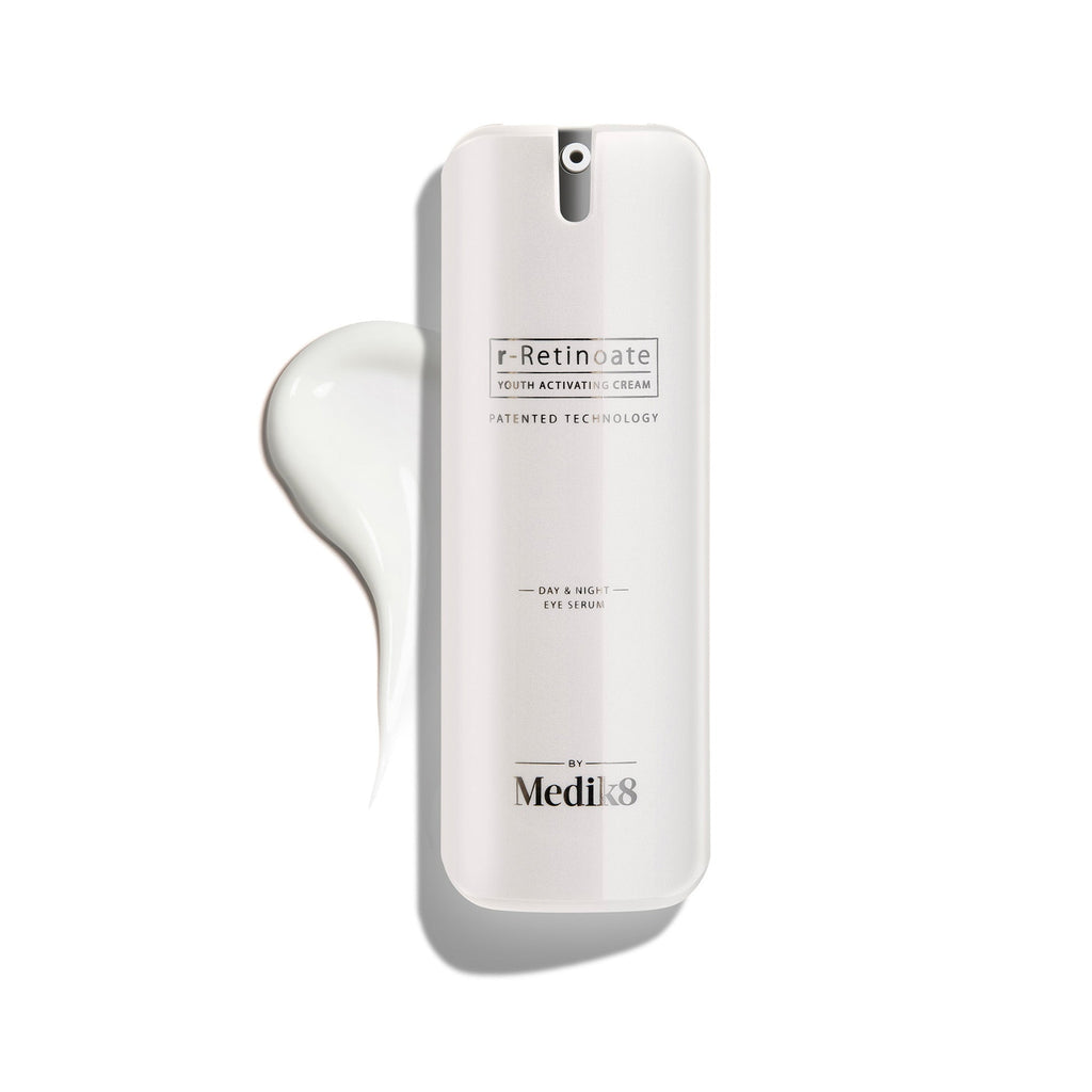 A white pump bottle of r-Retinoate Day & Night Eye Serum, with a droplet of product next to it.