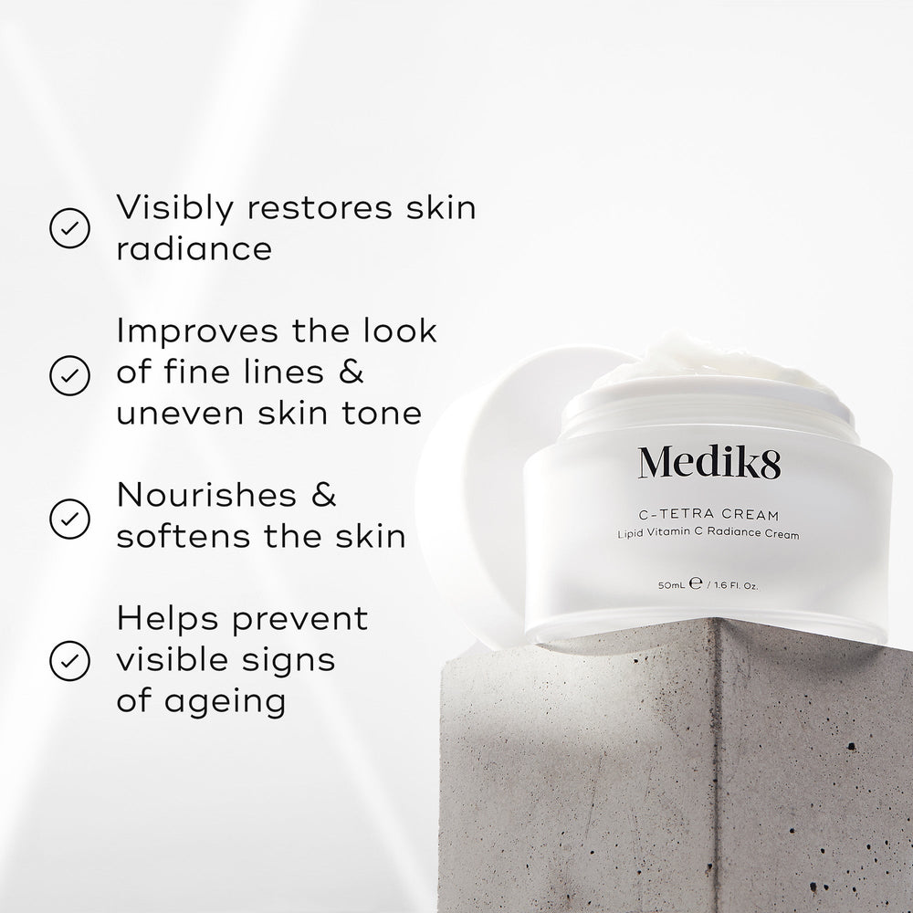 Medik8 C-Tetra Cream jar displayed on a grey stone block against a white background with soft light rays. The image features four check-marked claims:

Visibly restores skin radiance

Improves the look of fine lines & uneven skin tone

Nourishes & softens the skin

Helps prevent visible signs of ageing