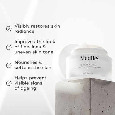 "Medik8 C-Tetra Cream jar displayed on a grey stone block against a white background with soft light rays. The image features four check-marked claims:

Visibly restores skin radiance

Improves the look of fine lines & uneven skin tone

Nourishes & softens the skin

Helps prevent visible signs of ageing"
