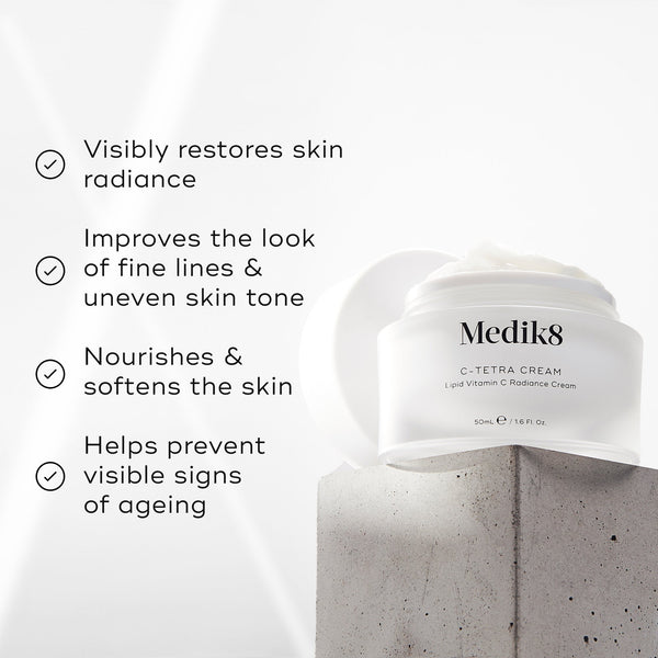 "Medik8 C-Tetra Cream jar displayed on a grey stone block against a white background with soft light rays. The image features four check-marked claims:

Visibly restores skin radiance

Improves the look of fine lines & uneven skin tone

Nourishes & softens the skin

Helps prevent visible signs of ageing"
