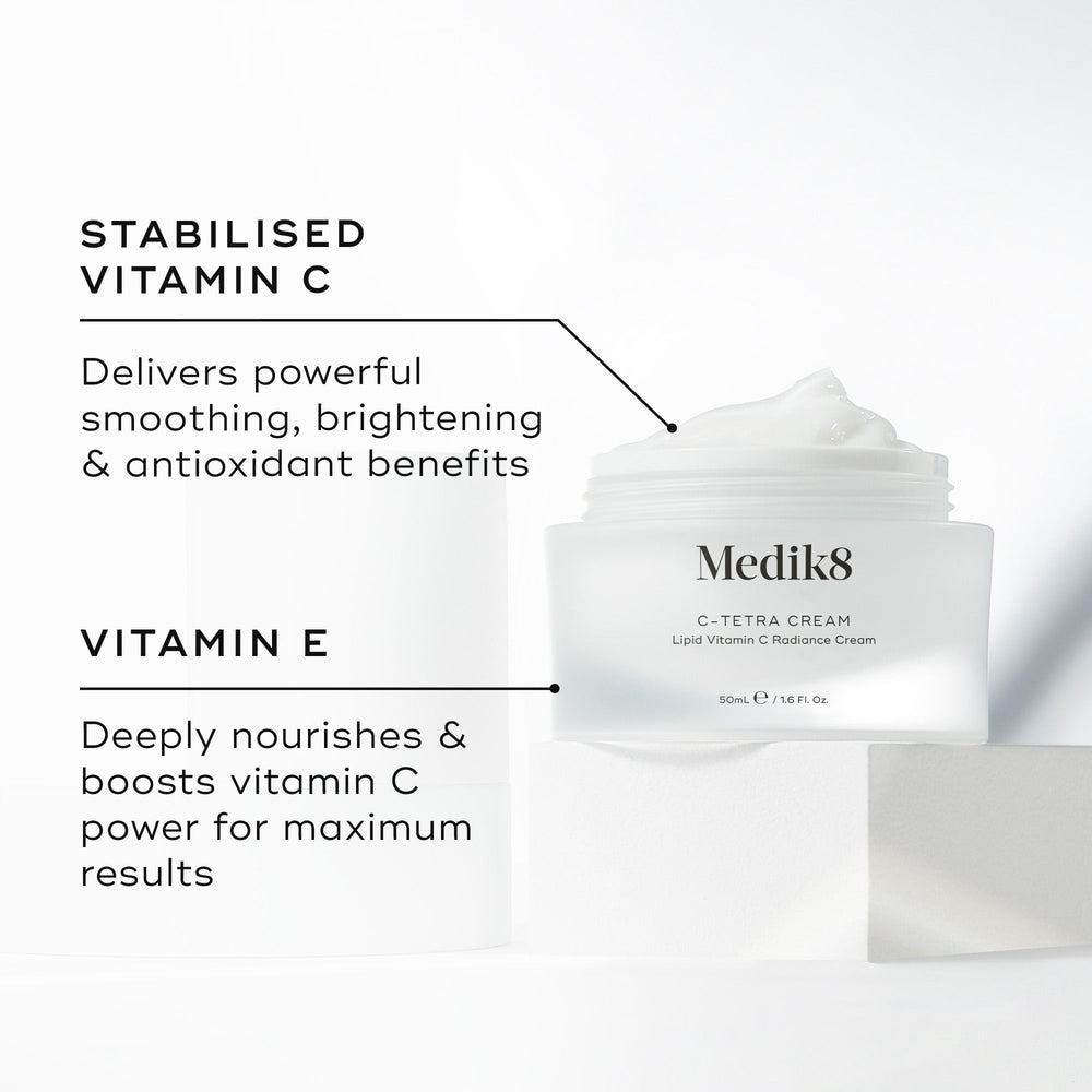 "Medik8 C-Tetra Cream jar displayed open on a white stone block against a clean white background. The image features two key ingredients and their benefits:

STABILISED VITAMIN C: Delivers powerful smoothing, brightening, and antioxidant benefits.

VITAMIN E: Deeply nourishes and boosts vitamin C power for maximum results."