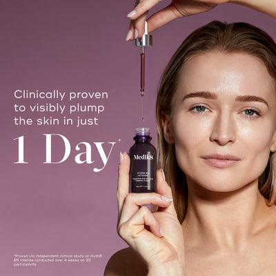 Medik8 Hydr8 B5 Intense glass dropper bottle centered on a shimmering purple background with translucent water droplets. Bold text states the product is clinically proven to visibly plump the skin in just 1 Day.