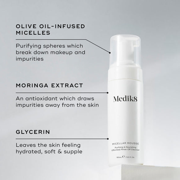 A Medik8 Micellar Mousse bottle displayed on a white block. Lines connect the bottle to text explaining key ingredients:  Olive Oil-Infused Micelles  to break down makeup,  Moringa Extract  to draw out impurities, and  Glycerin  for hydration.-hover-8