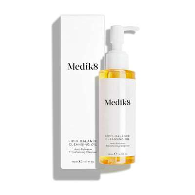 Medik8 Lipid-Balance Cleansing Oil bottle stands next to its white packaging carton. Text highlights the  Anti-Pollution Transforming Cleanser  formula and 140mL size.