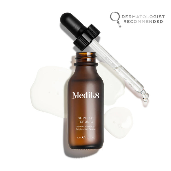 Medik8 Super C Ferulic serum bottle shown open with its glass pipette resting against the rim, displayed on a clean white background with translucent serum droplets. The amber glass bottle features the Medik8 logo and is labeled  SUPER C FERULIC Potent Vitamin C Brightening Serum  in a 30mL size.