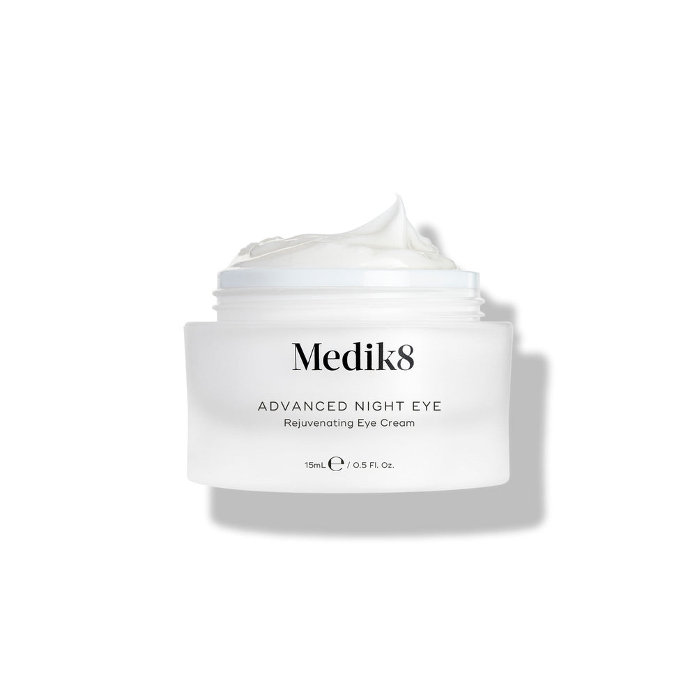 Medik8 Advanced Night Eye cream jar stands against a white background with the lid removed. The rich white cream is visible inside the jar, highlighting its texture.