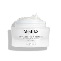 Medik8 Advanced Night Restore cream jar shown open with a rich dollop of white cream peaked on top against a clean white background, highlighting its smooth, restorative texture. Black text on the jar reads  Rejuvenating Multi-Ceramide Night Cream .