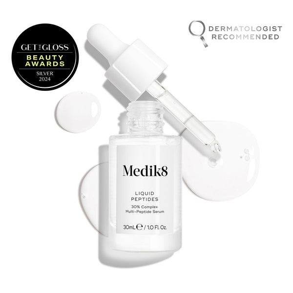 A clear glass dropper bottle of Liquid Peptides serum is presented, with its dropper removed and resting beside it and serum droplets, showing the texture