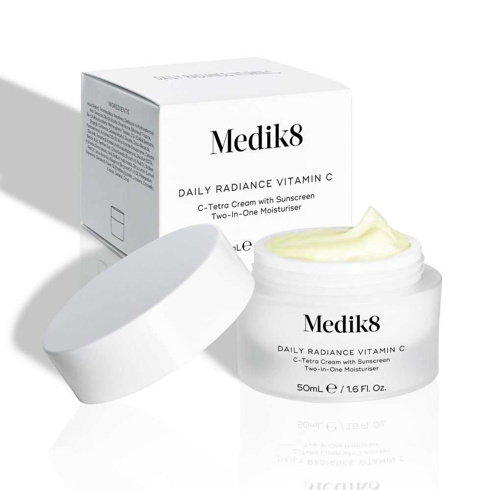 Medik8 Daily Radiance Vitamin C cream jar is shown open with a generous peak of pale yellow cream on top and it's carton packaging on the side. Text identifies the product as a 50mL C-Tetra Cream Two-in-One Moisturiser.