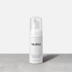 Bottle of Medik8 Clarifying Foam Refreshing AHA/BHA Blemish Cleanser stands against a grey and white background. The 40ml bottle has a clear cap and pump dispenser. 