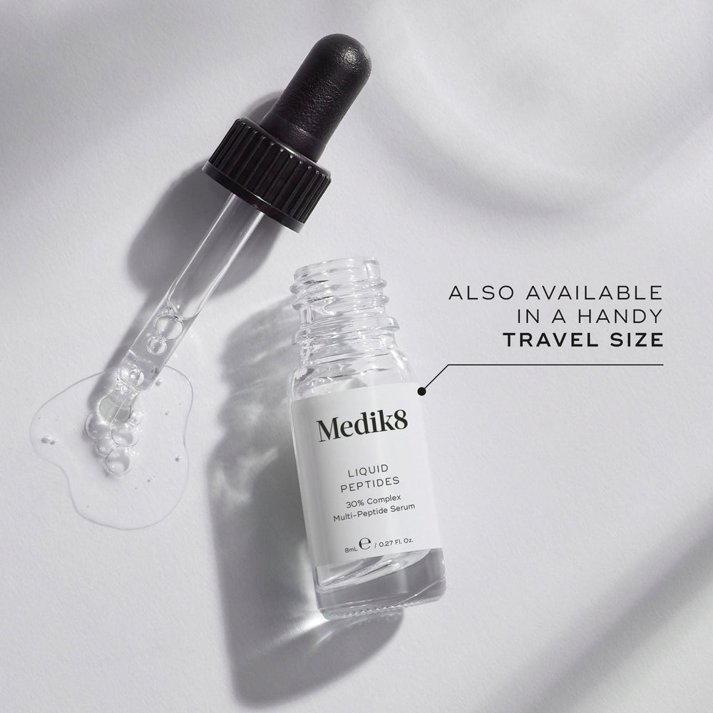 A small clear glass bottle (8mL) of Medik8 Liquid Peptides serum, with its dropper resting beside it. Text indicates it's  ALSO AVAILABLE IN A HANDY TRAVEL SIZE.