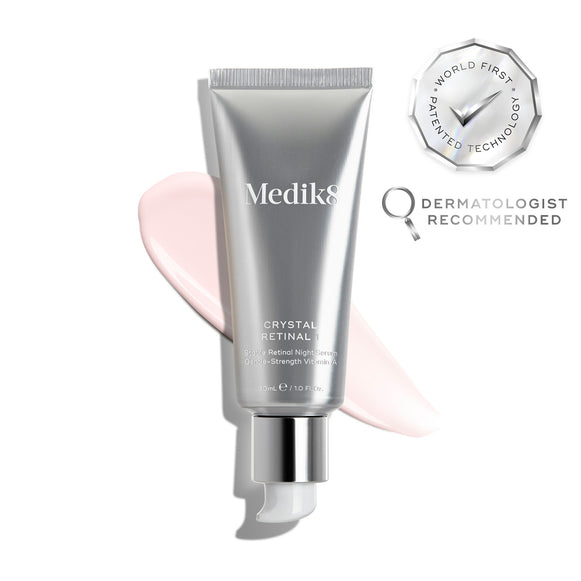 A silver tube of Crystal Retinal 1 is displayed, with a pink cream swatch to its right. A WORLD FIRST PATENTED TECHNOLOGY seal and a DERMATOLOGIST RECOMMENDED icon are shown. -1