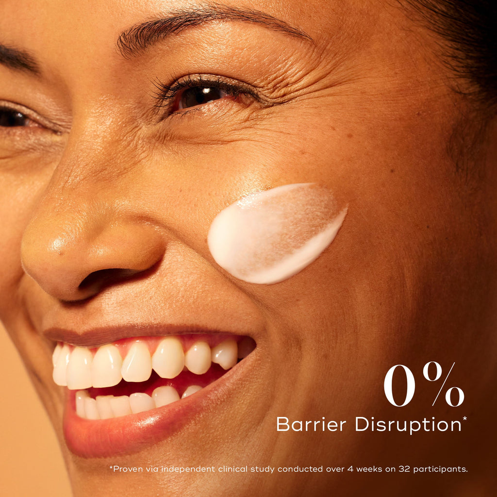 Smiling woman with radiant skin and a swipe of Medik8 C-Tetra Advanced serum on her cheek, emphasising 0% barrier disruption for gentle yet effective brightening.