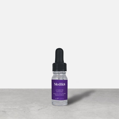 A purple 8ml glass dropper bottle of Medik8 HYDR8 B5 INTENSE serum stands next to its white packaging box on a grey surface against a white background. Text on both reads: "Medik8, HYDR8 B5 INTENSE, Hyaluronic Acid with NMF Replenish & Boost, 8mLe / 0.27 Fl. Oz.".