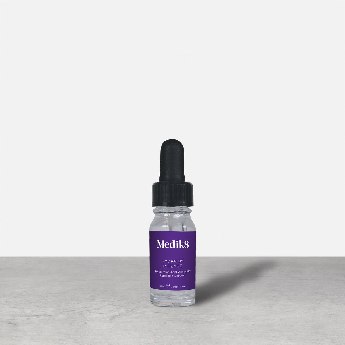 A purple 8ml glass dropper bottle of Medik8 HYDR8 B5 INTENSE serum stands next to its white packaging box on a grey surface against a white background. Text on both reads: "Medik8, HYDR8 B5 INTENSE, Hyaluronic Acid with NMF Replenish & Boost, 8mLe / 0.27 Fl. Oz.".