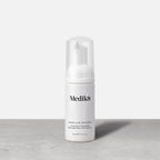 A travel-size pump bottle (40ml) of Medik8 Micellar Mousse displayed on a grey surface. Text describes it as a  Purifying & Nourishing Effortless Rinse-Off Cleanser. 