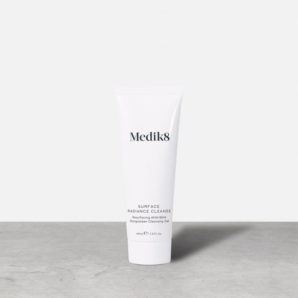 A single white tube of Medik8 Surface Radiance Cleanse stands on a grey surface. Label text includes: Medik8, SURFACE RADIANCE CLEANSE, Resurfacing AHA/BHA, Mangosteen Cleansing Gel, and 40mL℮ / 1.3 Fl. Oz.-24