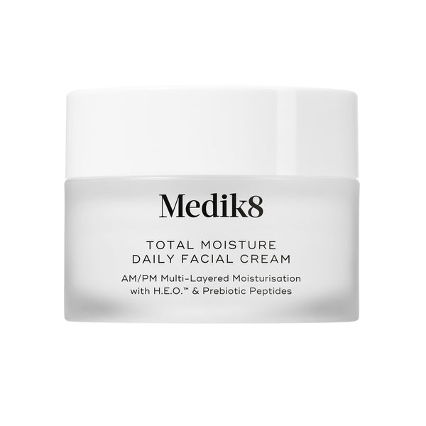 A travel-sized 12.5mL frosted jar of Medik8 Total Moisture Daily Facial Cream standing next to its white cardboard carton. The products are displayed on a textured grey surface against a clean white background. Text on both reads: "AM/PM Multi-Layered Moisturisation with H.E.O.™ & Prebiotic Peptides."